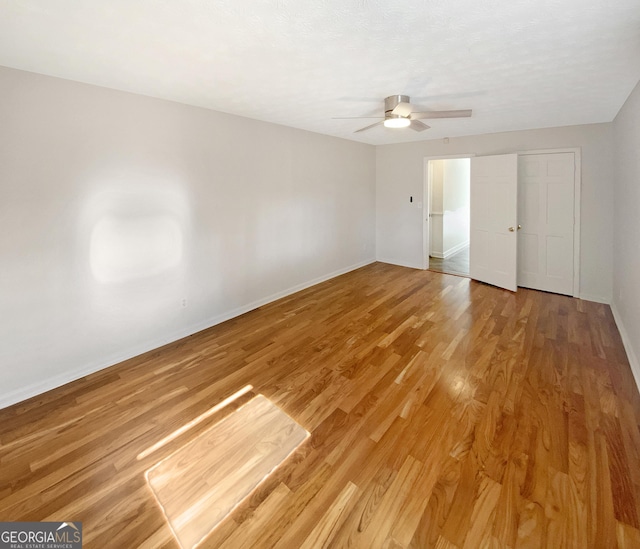 unfurnished bedroom with light wood-style flooring, a ceiling fan, and baseboards