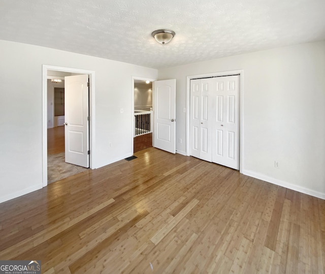 unfurnished bedroom featuring a closet, baseboards, a textured ceiling, and wood finished floors