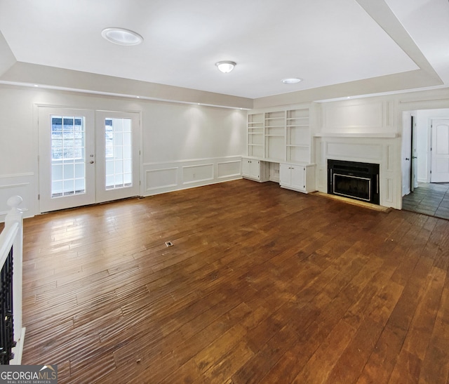 unfurnished living room with a decorative wall, a fireplace with raised hearth, and dark wood-style flooring