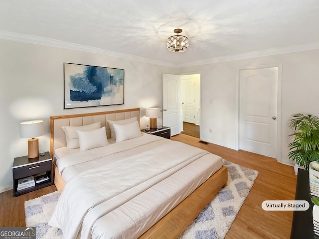 bedroom with a chandelier, crown molding, and wood finished floors