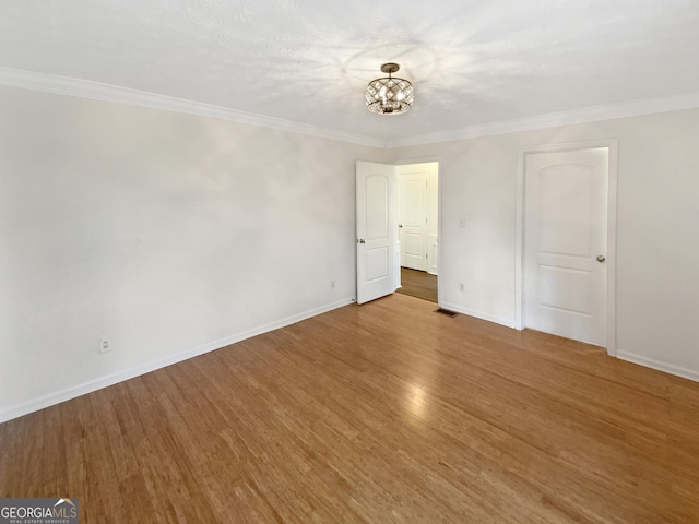 unfurnished room with visible vents, ornamental molding, an inviting chandelier, and wood finished floors