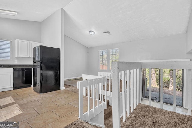 5338 Timor Trl, Lithonia, GA 30038 - kitchen featuring black appliances, vaulted ceiling, dark countertops, white cabinets, and light tile patterned floors