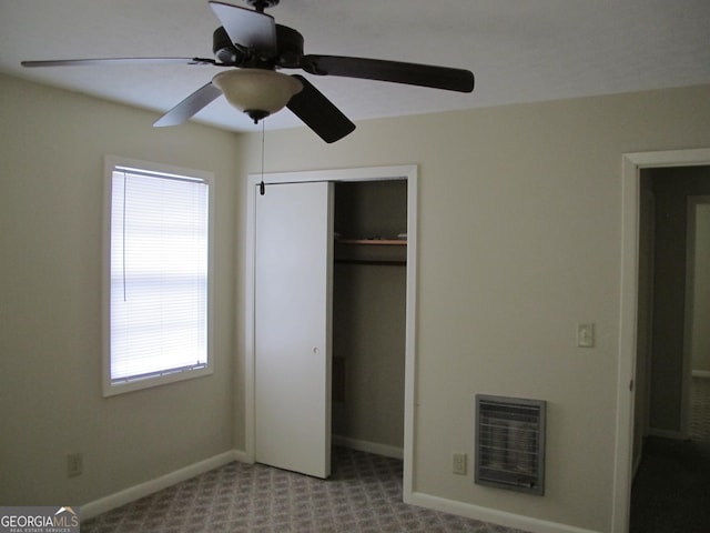 unfurnished bedroom featuring heating unit, baseboards, ceiling fan, a closet, and carpet flooring