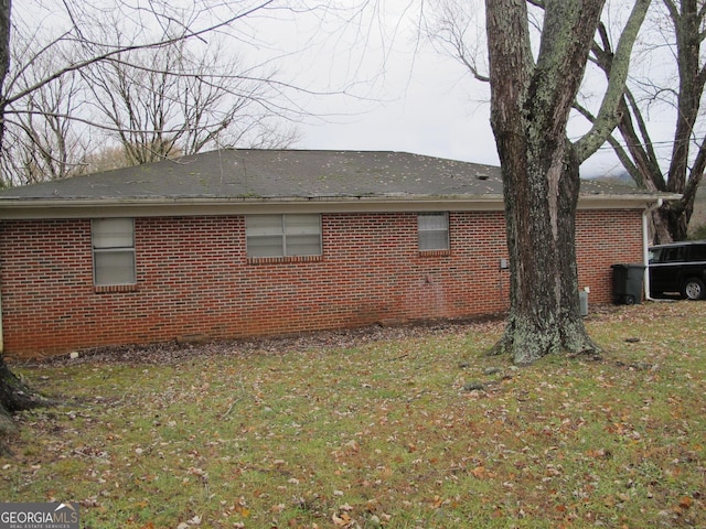 view of home's exterior with brick siding and a yard