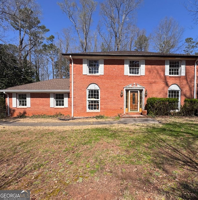 colonial house featuring brick siding and a front yard