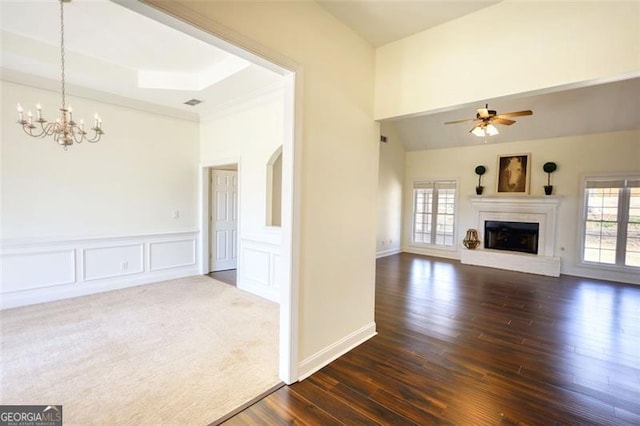 915 Cruce Lake Dr, Hoschton, GA 30548 - unfurnished living room with a fireplace with raised hearth, ceiling fan with notable chandelier, wainscoting, a decorative wall, and dark wood-style flooring