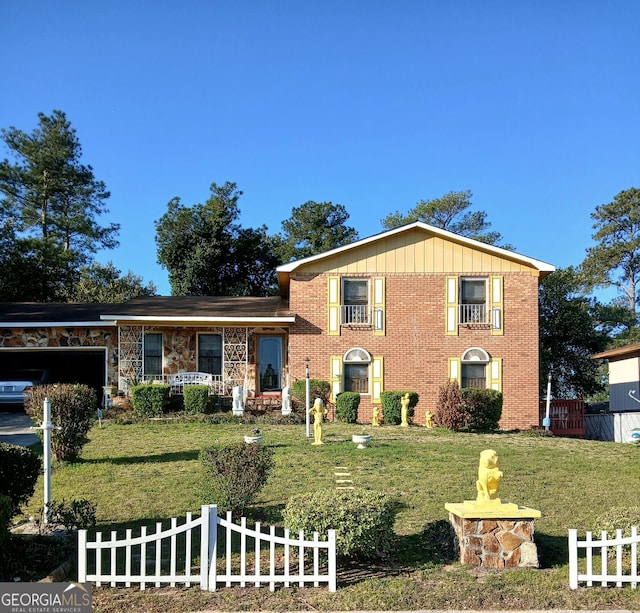 split level home featuring a front yard, brick siding, and a fenced front yard