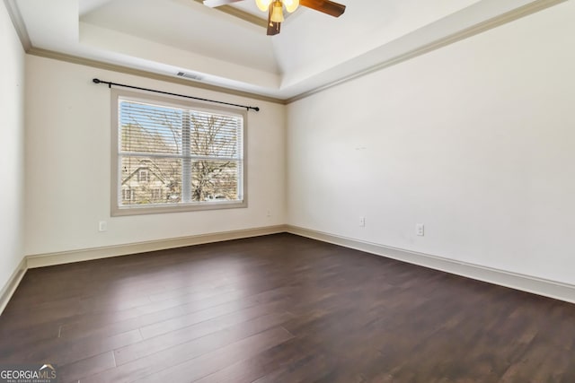 unfurnished room featuring visible vents, dark wood-style flooring, ceiling fan, ornamental molding, and a raised ceiling