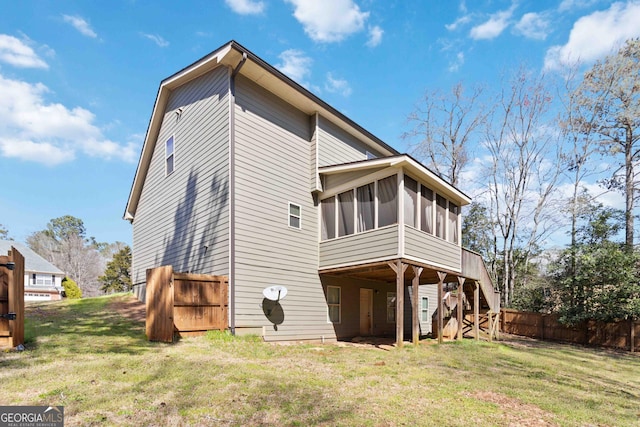 rear view of property featuring stairway, fence, a lawn, and a sunroom