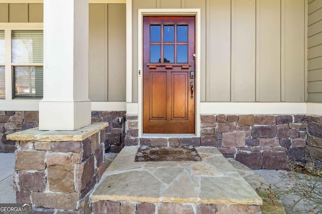 view of exterior entry featuring stone siding and board and batten siding