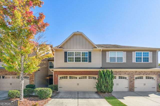 view of front of home featuring an attached garage, brick siding, board and batten siding, and driveway