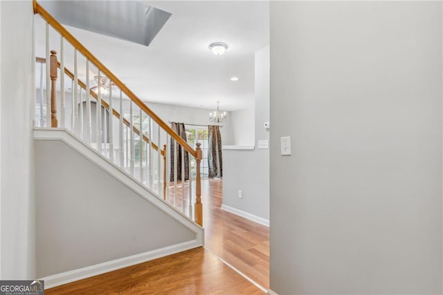 staircase with a chandelier, baseboards, and wood finished floors