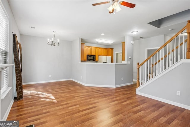 unfurnished living room with visible vents, light wood-type flooring, ceiling fan with notable chandelier, stairway, and baseboards