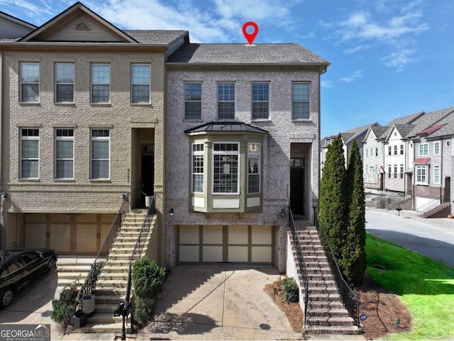 townhome / multi-family property featuring stairs, brick siding, a garage, and driveway