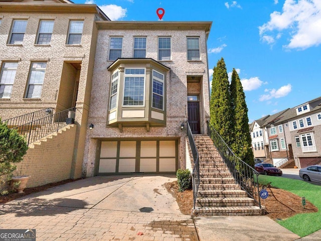 view of property featuring stairway, brick siding, and driveway