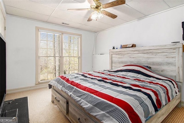 carpeted bedroom with baseboards, visible vents, a drop ceiling, and ceiling fan