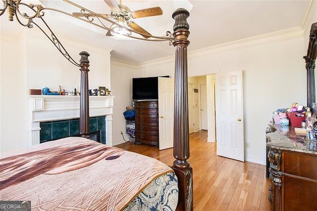 bedroom featuring ceiling fan, light wood-style floors, a tile fireplace, and ornamental molding