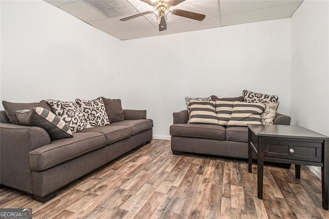 living room with a drop ceiling, baseboards, a ceiling fan, and wood finished floors