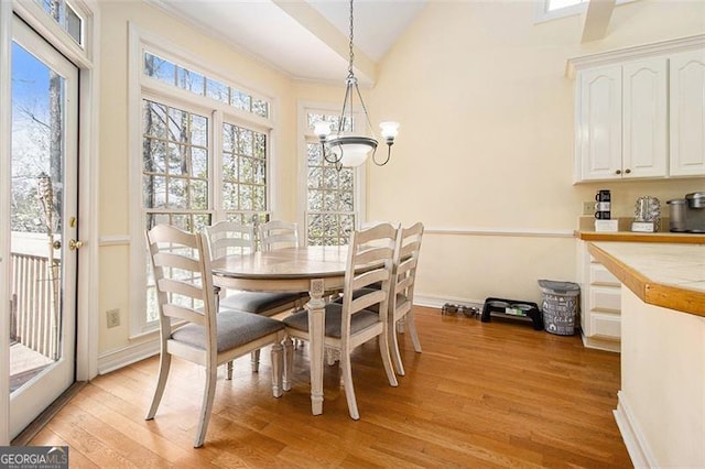 dining room featuring baseboards, an inviting chandelier, light wood-style flooring, and vaulted ceiling