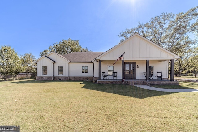 modern farmhouse style home featuring covered porch, board and batten siding, a front yard, and roof with shingles