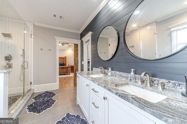 ensuite bathroom with crown molding, visible vents, a shower stall, and a sink