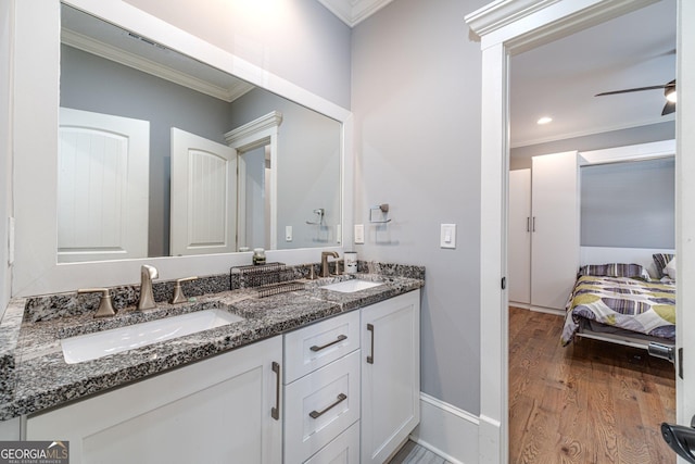 full bathroom with double vanity, ornamental molding, wood finished floors, and a sink