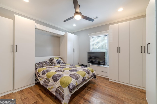 bedroom featuring light wood-style floors, visible vents, and ornamental molding