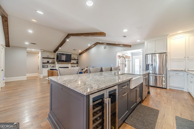 kitchen featuring wine cooler, vaulted ceiling, light wood-style flooring, stainless steel appliances, and a sink