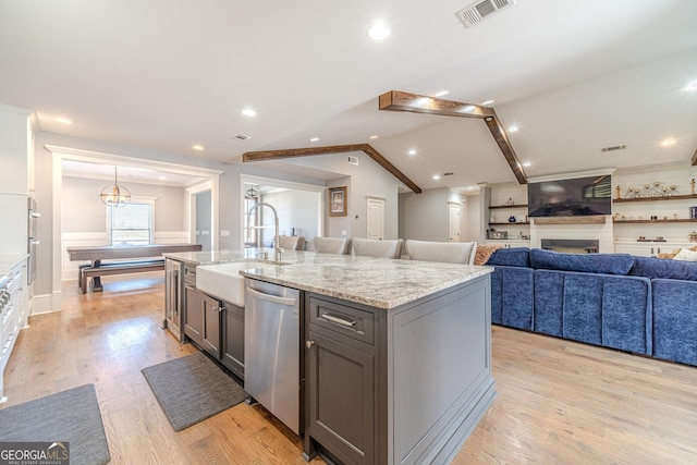 kitchen featuring visible vents, a sink, vaulted ceiling, light wood-style floors, and stainless steel dishwasher