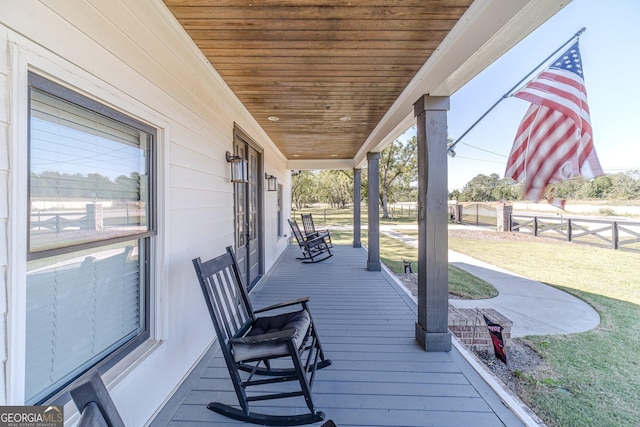 wooden deck featuring covered porch and fence