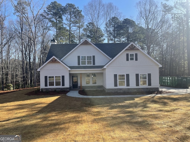 craftsman house featuring a chimney, a front yard, and a shingled roof