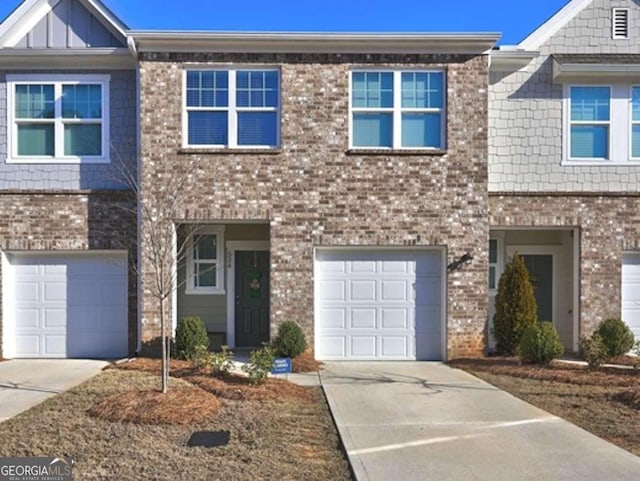 multi unit property with board and batten siding, concrete driveway, an attached garage, and brick siding