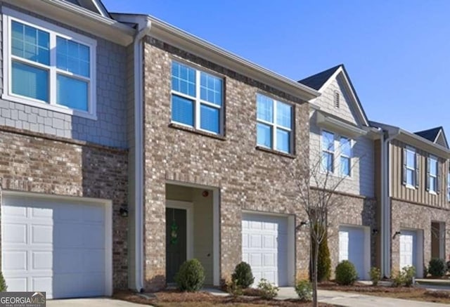 view of property with brick siding, concrete driveway, and an attached garage