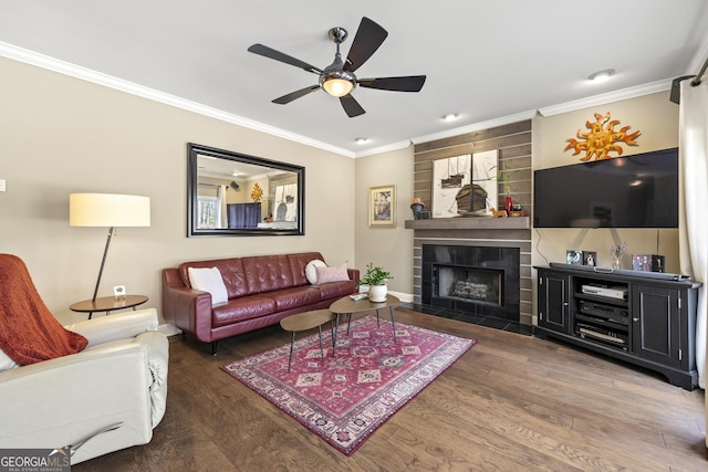 living room with a ceiling fan, wood finished floors, baseboards, ornamental molding, and a tiled fireplace