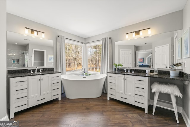 bathroom featuring a sink, two vanities, a stall shower, and wood finished floors