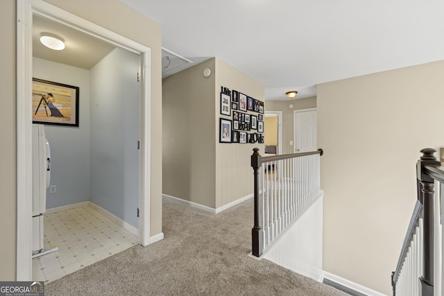 corridor with baseboards, an upstairs landing, and carpet floors