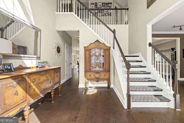 stairs with a high ceiling, wood finished floors, baseboards, and ornamental molding