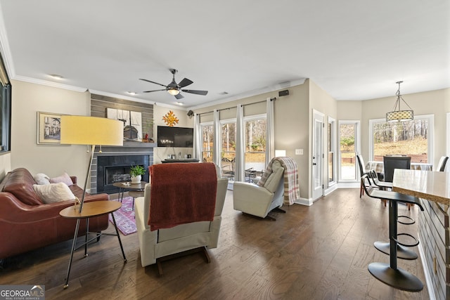 living room featuring ornamental molding, a ceiling fan, dark wood-style floors, baseboards, and a tile fireplace