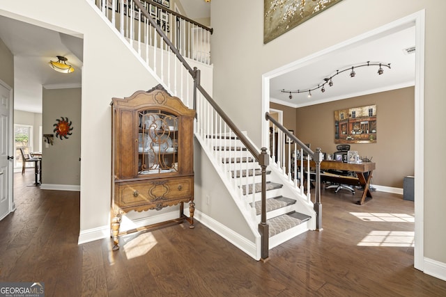 stairway featuring visible vents, hardwood / wood-style flooring, crown molding, baseboards, and a towering ceiling