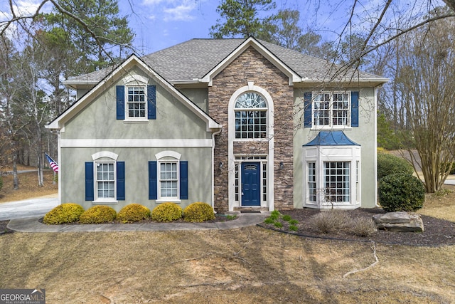 view of front of house featuring stucco siding, stone siding, and a shingled roof