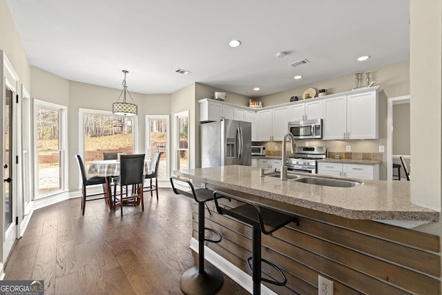 kitchen featuring a sink, stainless steel appliances, visible vents, and dark wood finished floors