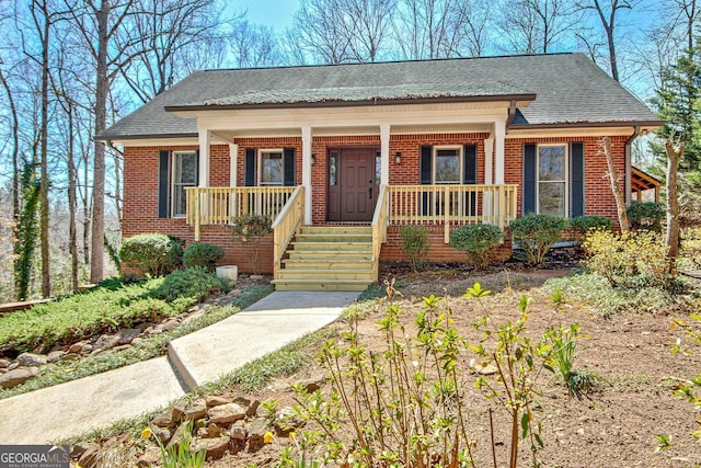 view of front of home featuring brick siding, a porch, and a shingled roof