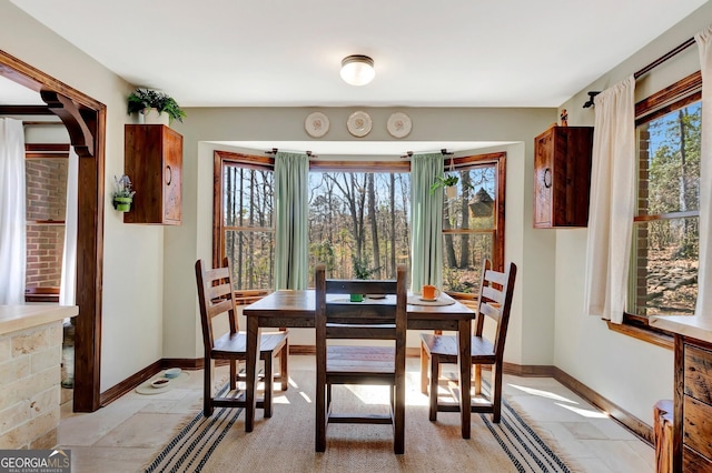 dining area with stone tile flooring, plenty of natural light, and baseboards