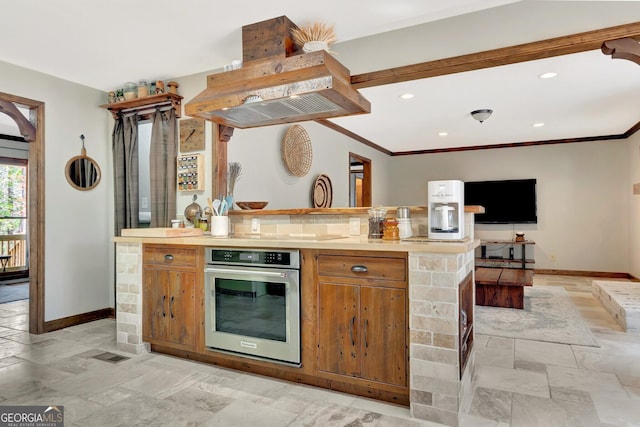 kitchen with brown cabinets, open floor plan, baseboards, and oven