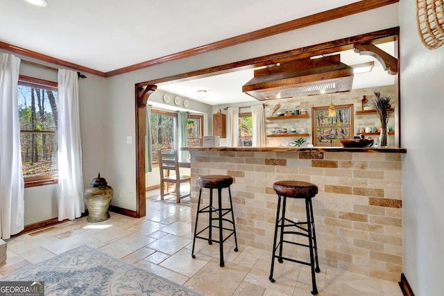 kitchen with stone tile flooring, plenty of natural light, a breakfast bar, and baseboards