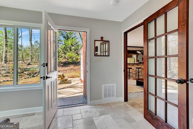 foyer with stone tile flooring, visible vents, plenty of natural light, and french doors