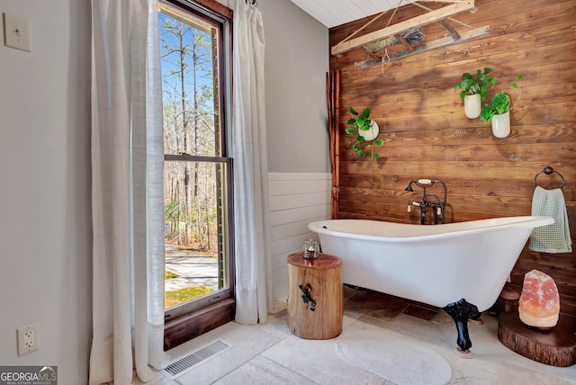 full bathroom with visible vents, a soaking tub, wood walls, and wainscoting