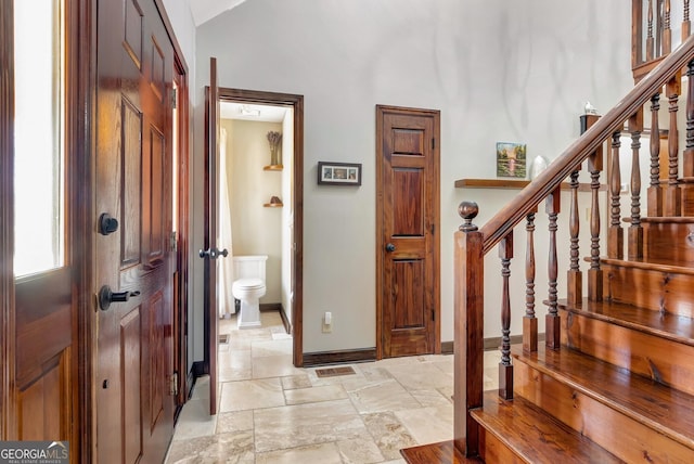 entryway featuring stairs, lofted ceiling, baseboards, and stone tile flooring