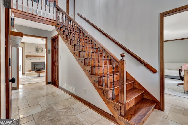 stairway featuring stone tile flooring, visible vents, baseboards, and a towering ceiling