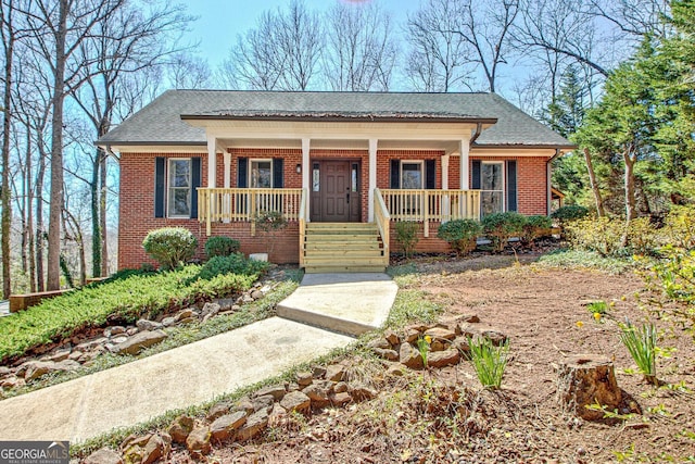 view of front of property featuring brick siding, a porch, and roof with shingles